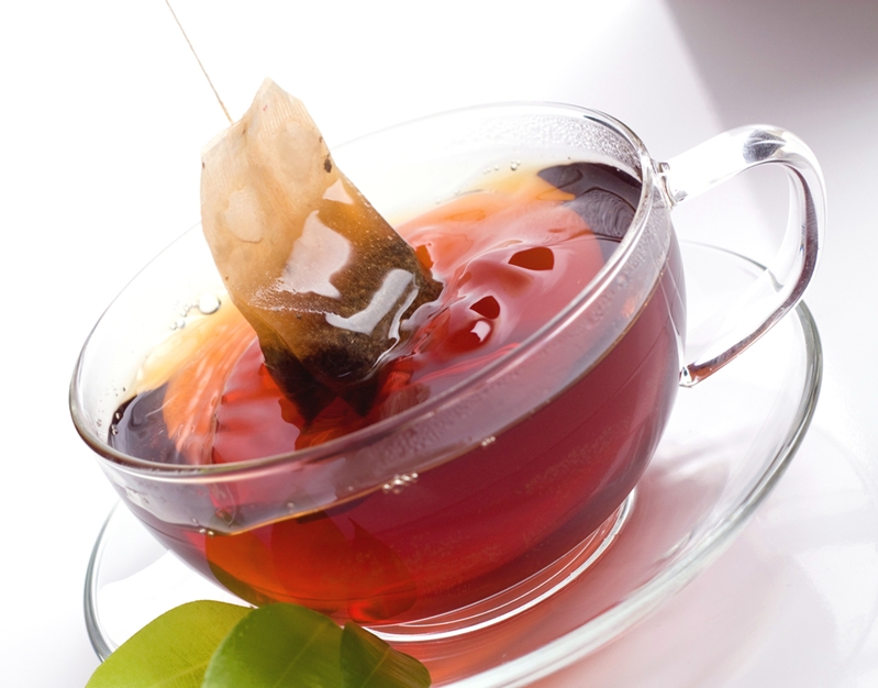 Tea bag dipped in cup of red tea.