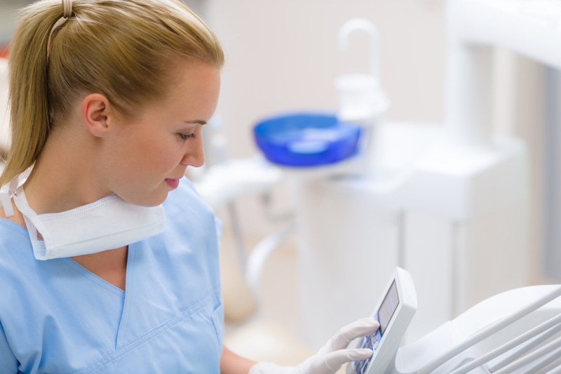 Dental assistant looking at computer.