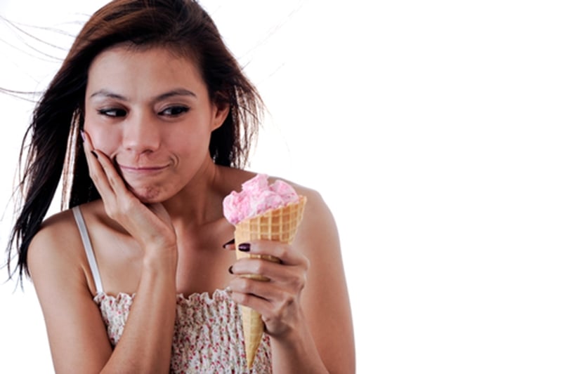 Girl eating ice cream and experiencing sensitivity.