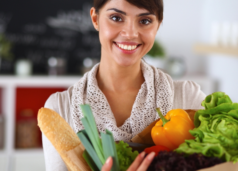 Women holding vegetables and smiling.