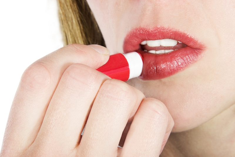 Girl applying chap stick to prevent chapped lips.