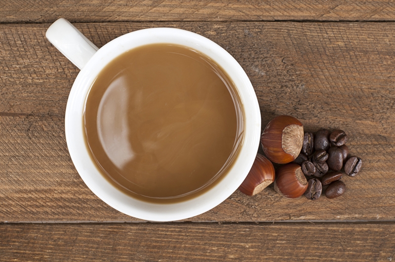 Cup of coffee on table with hazelnut.