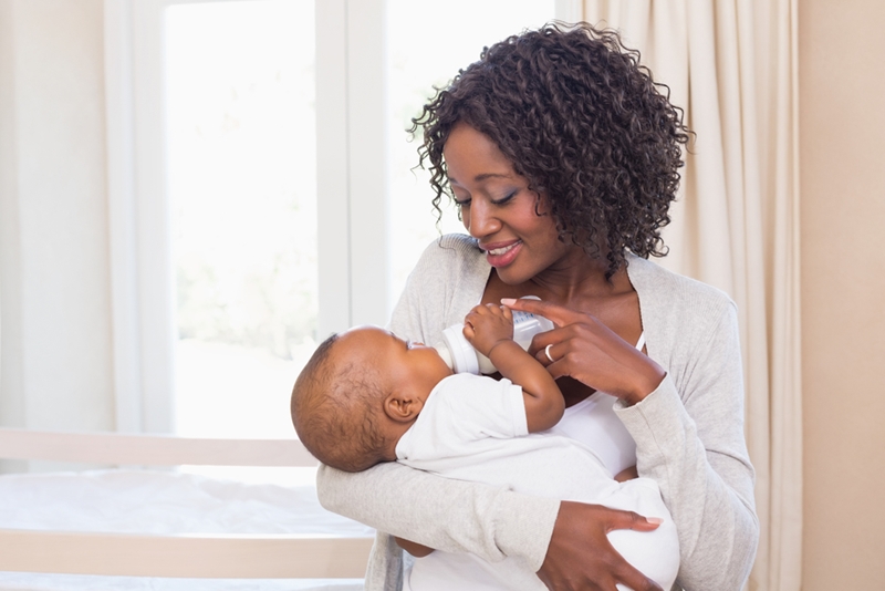 Mom smiling at baby while bottle feeding.