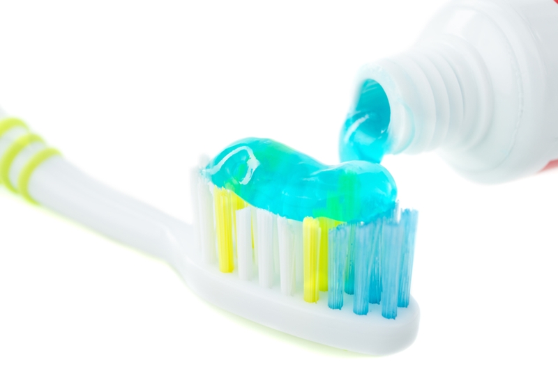 Toothbrush covered in blue toothpaste. 