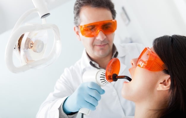 Dentist_fixing_cavity on a female patient using laser.jpeg