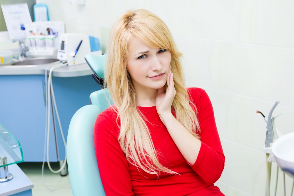 Closeup portrait sad, young girl, woman with painful tooth, ache in medical office siting in chair