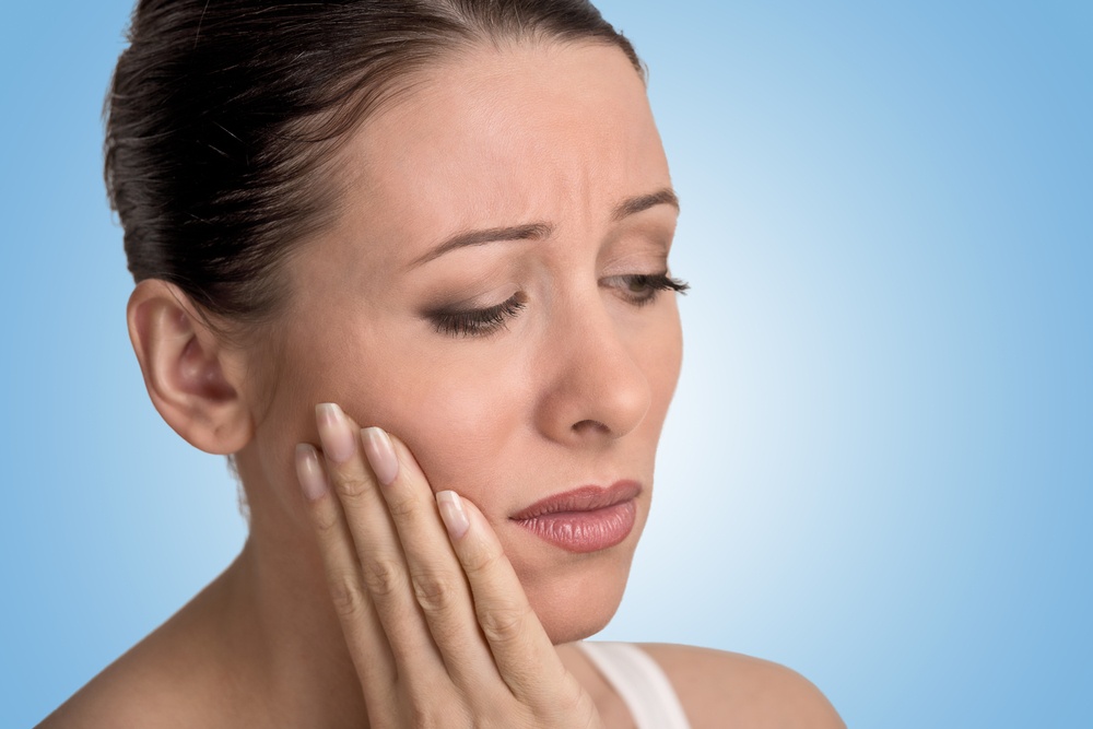 Closeup portrait young woman with sensitive tooth ache crown problem about to cry from pain touching outside mouth with hand isolated blue background. Negative emotion facial expression feeling.jpeg