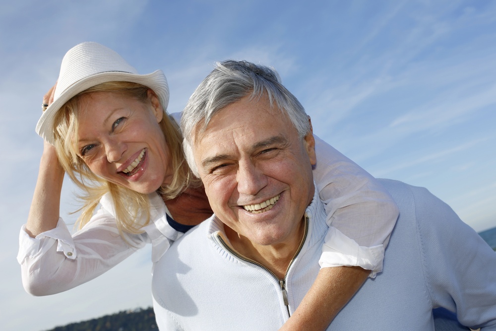 Cheerful senior couple having fun at the beach and smiling