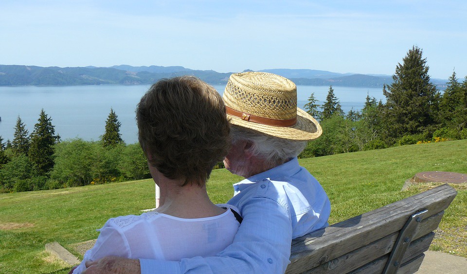 Senior Dental Health - Elderly couple on bench looking at a lake